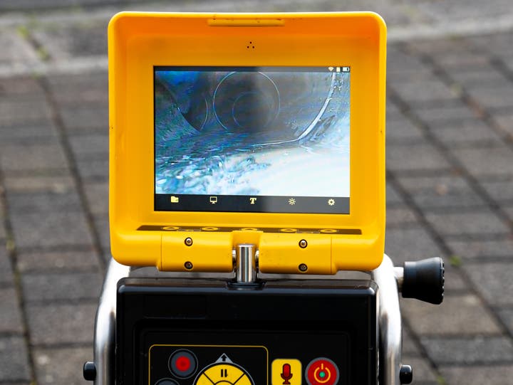 A camera is being used to inspect the interior of a drain line. The image shows the camera's view, revealing the condition of the pipe, which may include blockages, cracks, or buildup. This inspection is crucial for diagnosing plumbing issues and planning necessary repairs or maintenance.